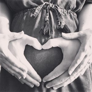 Picture of hands in a heart shape over a baby bump