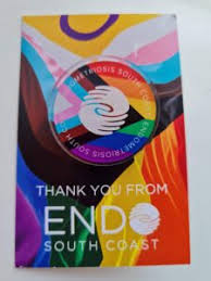 a colourful card with a charity logo pin